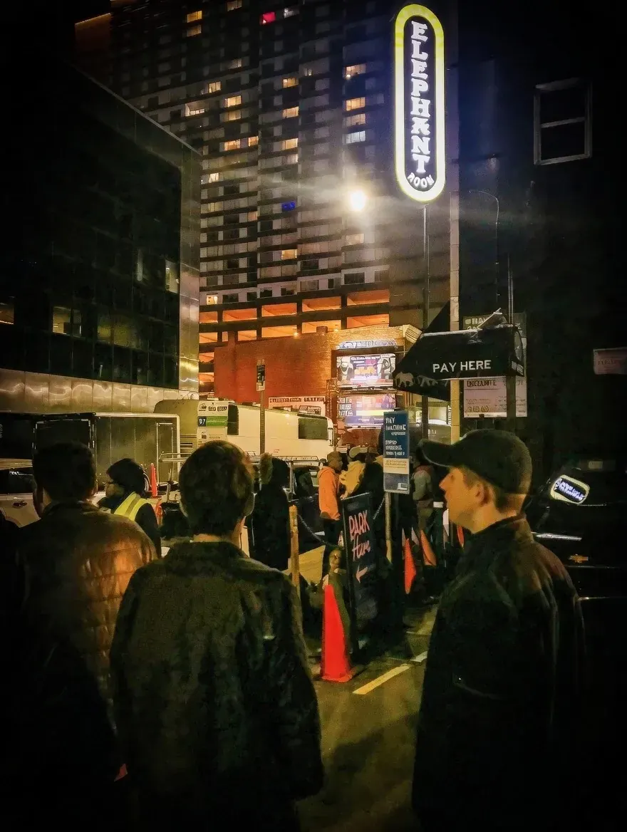 People queuing outside illuminated hotel at night